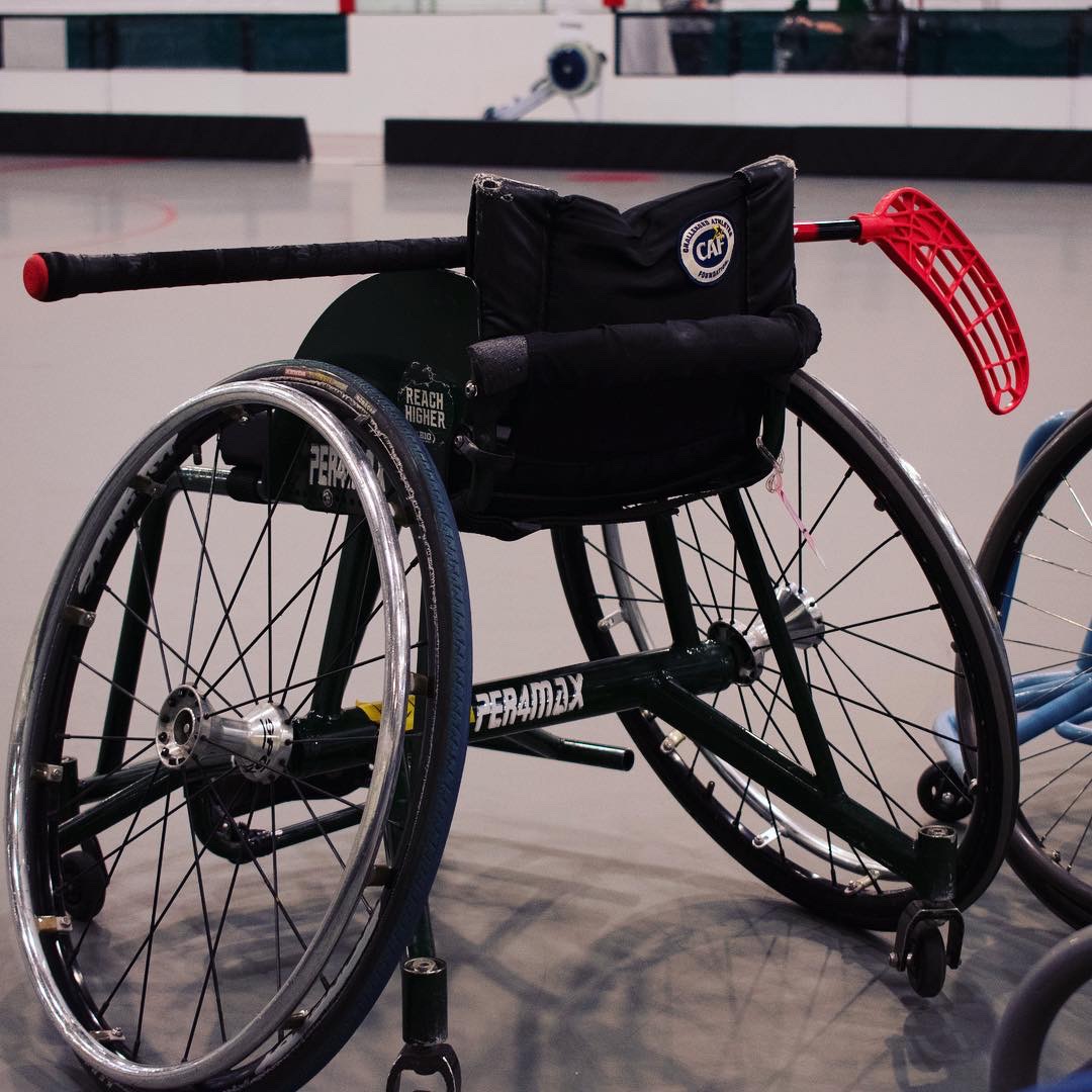 A wheelchair holding a hockey stick